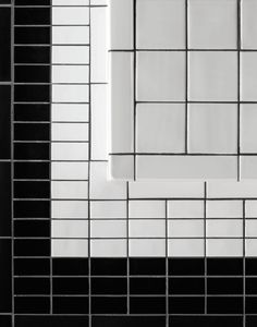 a black and white tiled bathroom wall with square tiles on the bottom, and rectangular tile in the middle