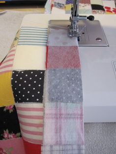 the sewing machine is sitting on the table next to the quilts and fabrics that have been sewn together