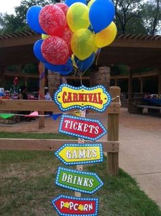 a bunch of balloons that are on top of a wooden post in front of a building