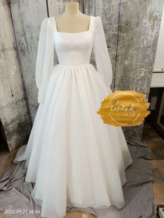 a white wedding dress with long sleeves on display