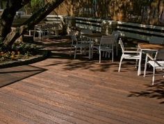 a wooden deck with chairs and tables under a tree