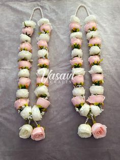 two pink and white roses are attached to the same string as other flowers, on a gray background