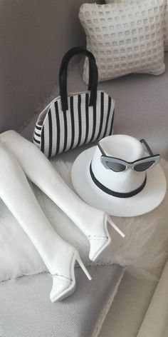 a hat, sunglasses and purse sitting on top of a bed