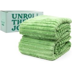 three green towels stacked on top of each other next to a box of unroll the joc