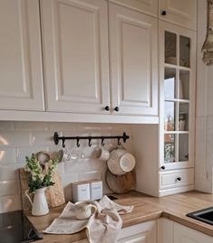 a kitchen with white cabinets and wooden counter tops