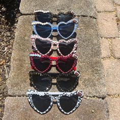 three pairs of heart shaped sunglasses sitting next to each other on top of a sidewalk