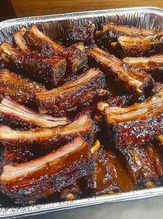 barbecue ribs in tin foil sitting on top of a table