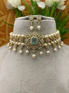 a necklace and earring set with pearls on a white mannequin neck piece