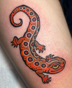 an orange and black lizard tattoo on the leg