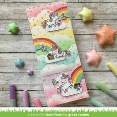 a card with unicorns and rainbows on it, surrounded by crayons