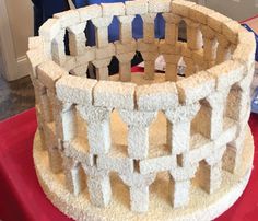 a model of a castle made out of foam blocks on a red table with a person standing in the background