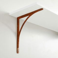 a wooden shelf mounted to the side of a white wall with a curved corner on it