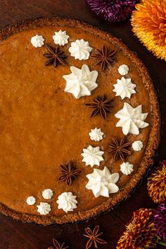 a chocolate pie with white frosting and star anisettes on top, surrounded by flowers