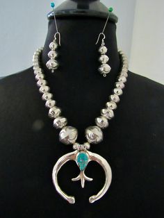 This striking set consists of a cast sterling silver naja with a fleur-de-lis center and channeled turquoise inlay on a strand of graduated and stamped, handmade sterling silver bench beads (also known as "Navajo Pearls") with matching earrings.  The naja measures 2 1/4 (two and one quarter) inches by 2 1/4 (two and one quarter) inches.  The turquoise portion is 5/8 (five eighths) of an inch by 7/16 (seven sixteenths) of an inch. Laid flat in a straight line, the handmade, sterling silver bench bead necklace measures 20 (twenty) inches from end of hook to end of eye.  You can also judge the relative length and size of this necklace by the fact that I have photographed it on a contemporary size 6 - 8 dress form.  The beads in the necklace are 7/8, 5/8, 1/2 and 3/8 of an inch in diameter.  T Real Turquoise Jewelry, Inlay Jewelry, French Wire, Western Jewelry, Native American Jewelry, Handmade Sterling Silver, Turquoise Jewelry, Matching Earrings, Antique Jewelry