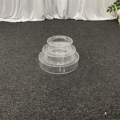 three clear plates sitting on top of a carpeted floor next to a vase with flowers