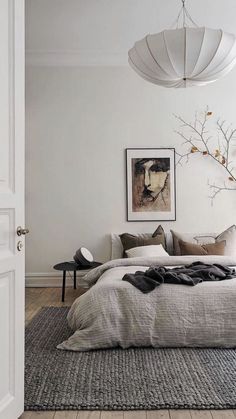 a bedroom with white walls and wooden flooring has a large bed in the middle