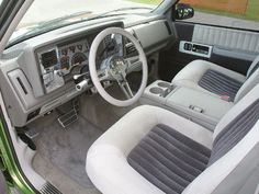 the interior of a car with grey and white leather seats, steering wheel and dashboard