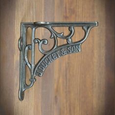 a metal shelf bracket on a wooden door with the word sweet & son written in it