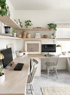 a desk with a computer on top of it next to two chairs and a window