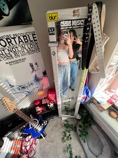 two people standing in front of a mirror with guitars and other items on the floor