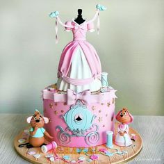 a pink and white cake with a princess dress on top, surrounded by other toys