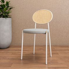 a white chair sitting next to a potted plant on top of a wooden floor