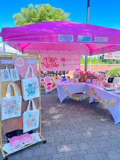 there is a pink and white tent that has bags on the table under it,