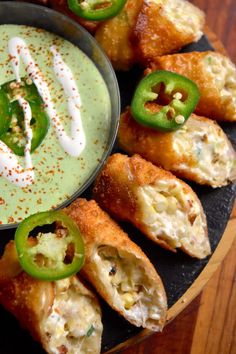 some food is on a black plate with green peppers and sauce in the bowl next to it