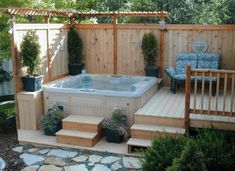 a hot tub sitting in the middle of a garden next to a wooden fence and steps