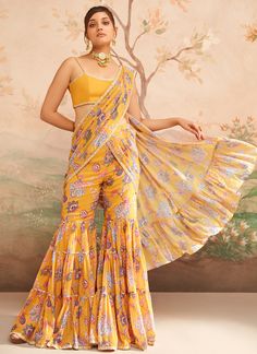 Mustard Yellow Floral Printed Pant Saree includes a georgette blouse and georgette with santoon inner saree. Embroidery is present on this style using thread, stone, print, zari, and hand work. Like all of our pieces, this piece is made in India and checked by hand to ensure high quality. Georgette Pre-draped Saree With Dupatta For Diwali, Bollywood Style Choli With Printed Motifs, Yellow Georgette Sets With Printed Motifs, Festive Georgette Sets With Printed Motifs, Fitted Georgette Choli With Printed Motifs, Yellow Saree Set With Printed Motifs, Fitted Pre-draped Saree With Printed Motifs In Georgette, Yellow Sharara With Printed Motifs For Navratri, Semi-stitched Printed Motif Sharara For Diwali