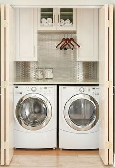 a washer and dryer in a small room with white cupboards above them