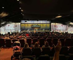 an auditorium filled with lots of people sitting in chairs