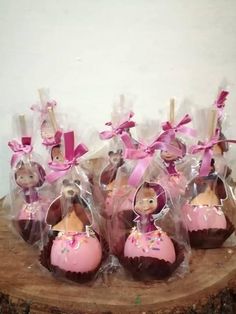 chocolates wrapped in cellophane and decorated with pink bows are sitting on a tree stump