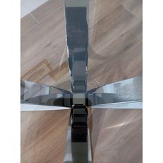 a glass table with two knives on top of it and wood flooring in the background