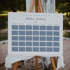 an easel with a baby jones calendar on it sitting in front of a tree