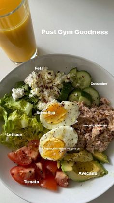 a white plate topped with salad next to a glass of orange juice