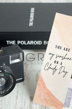 a polaroid camera sitting next to two books and a card that says, you are my sunshine on a cloudy day