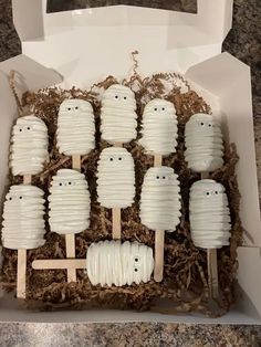 a box filled with white marshmallows in the shape of ghost faces and heads