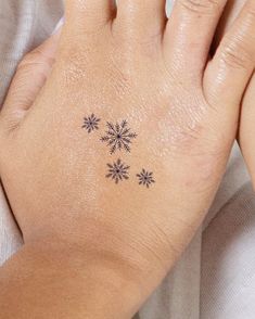 a woman's hand with a snowflake tattoo on her left wrist and fingers