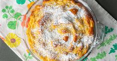 a pie covered in powdered sugar on top of a white cloth next to a fork