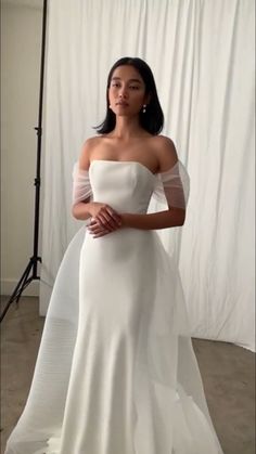 a woman in a white wedding dress posing for a photo with her hands on her hips