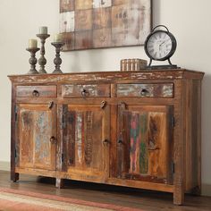 an old wooden sideboard with two candles and a clock on top