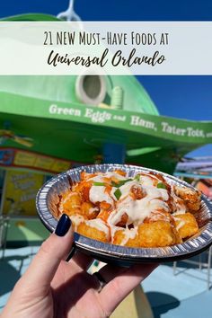 a person holding a plate with food on it and the words, 21 new must - have foods at universal orlando