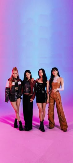 four women standing in front of a blue and pink background wearing black leather outfits, one with her arms around the other's waist