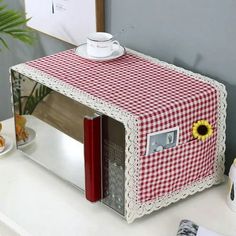 a microwave with a red and white checkered table cloth on it's side