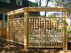 a wooden pergola in front of a house with trees and bushes around it