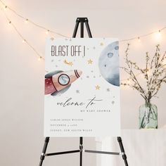 an easel with a sign that says blast off, welcome to the baby shower