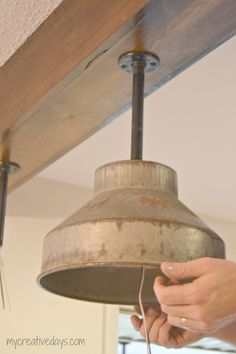 a person is holding a light fixture in their hand and it's attached to the ceiling