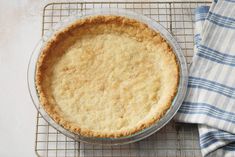 a pie sitting on top of a cooling rack next to a blue and white towel