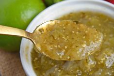 a spoon with some food in it next to limes and other fruit on the table